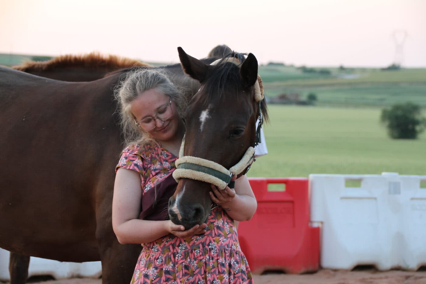Cellia et un cheval bai partagent un moment de tendresse en fin de journée - garde de chevaux CelliaCare